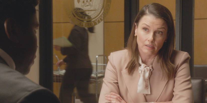 Erin Reagan, played by Bridget Moynahan, sits in a peach top speaking to a student in Blue Bloods