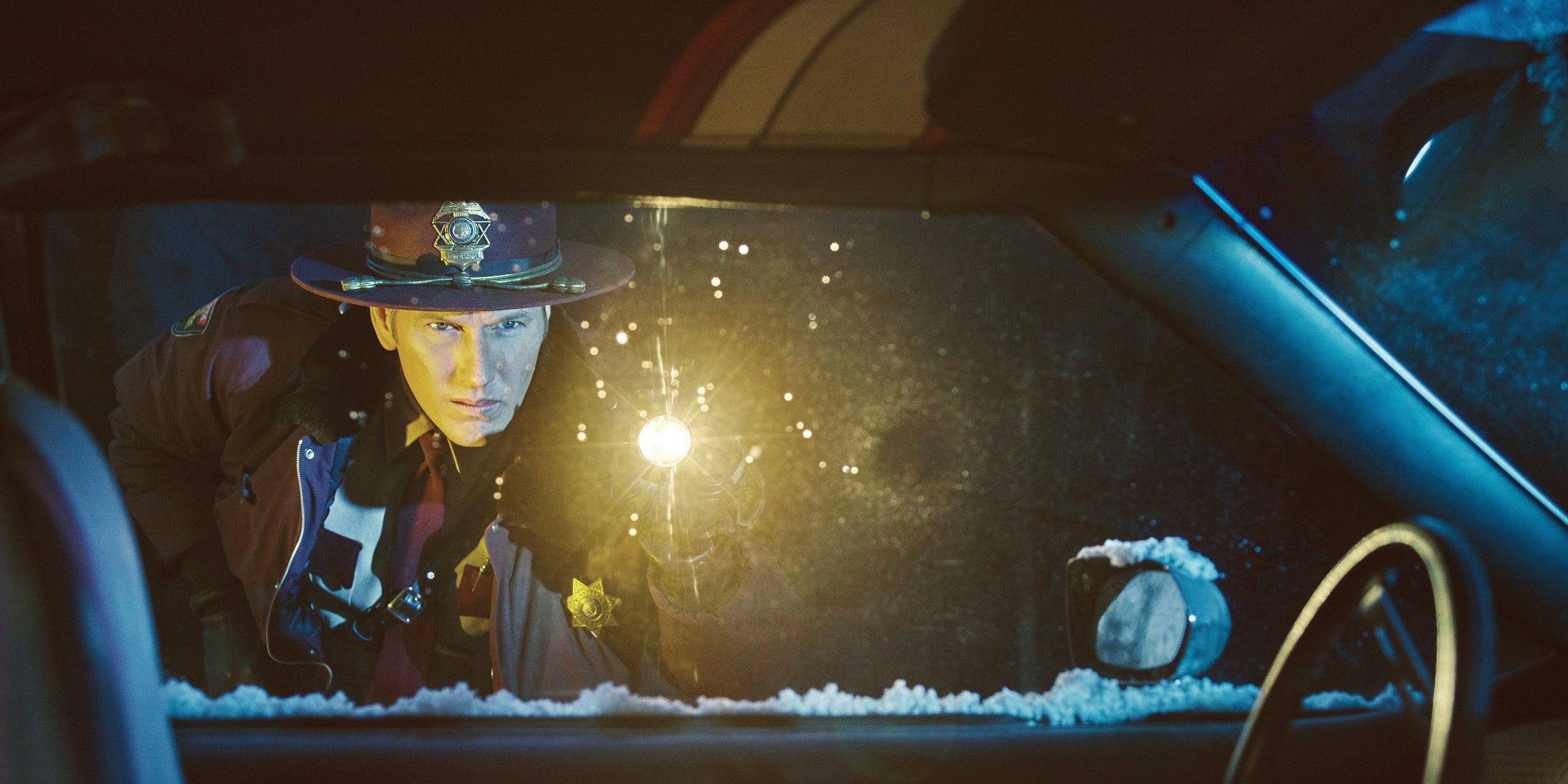 Patrick Wilson as Lou Solverson in Fargo Season 2 looks into a car with his flashilight.