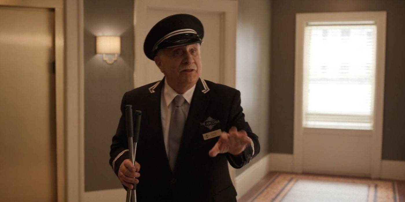 Teddy trying to talk to someone, his hand out, in the lobby of the Arconia on Only Murders in the Building.