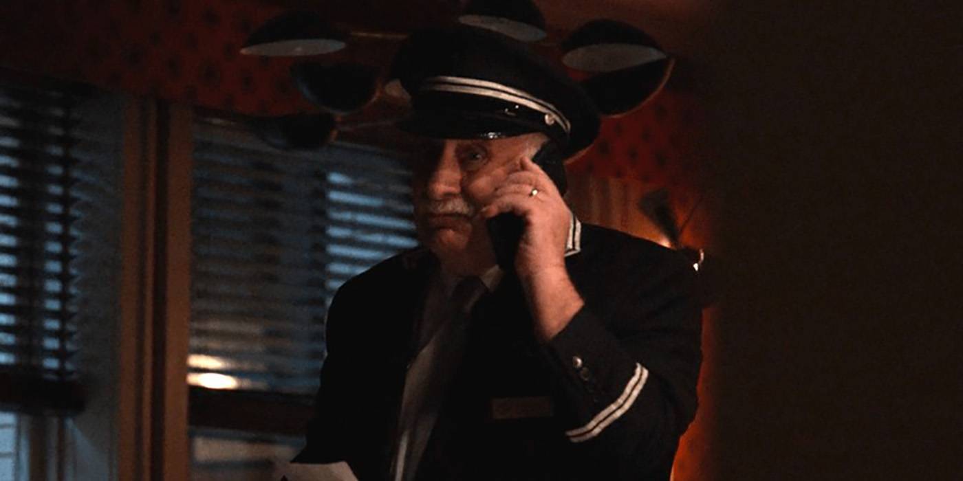 Lester from Only Murders in the Building in an apartment on the phone in the dark.