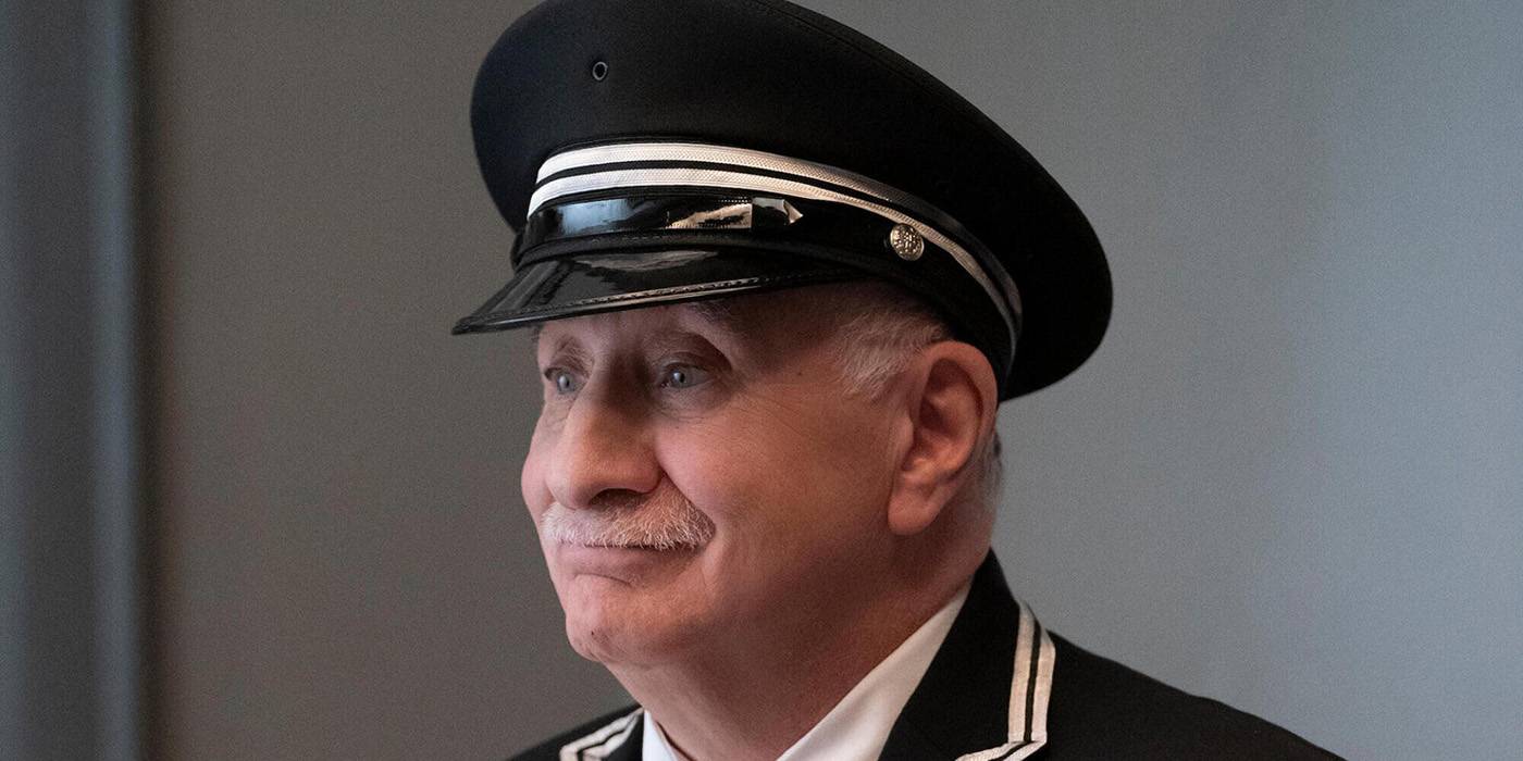 A side profile of Teddy smiling in Only Murders in the Building.