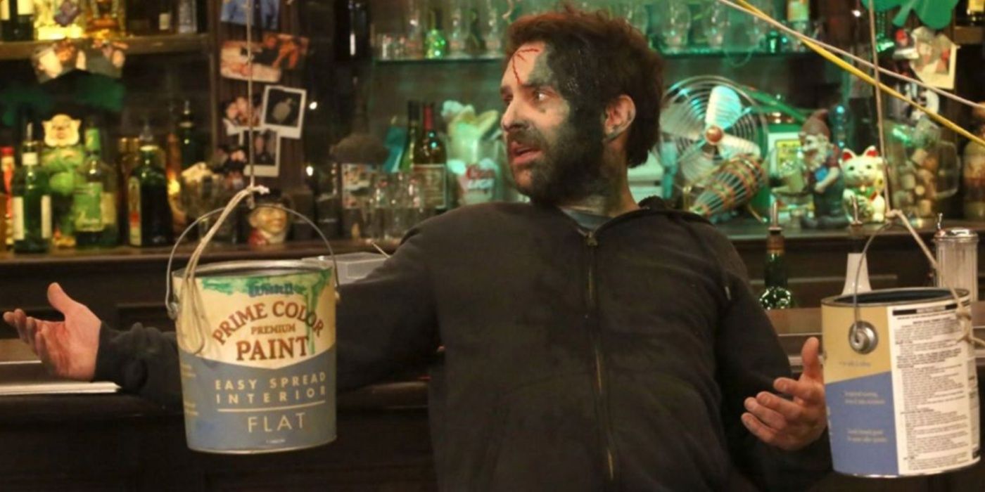 Charlie posando coberto de tinta verde com dois baldes de tinta ao lado dele, de It's Always Sunny.