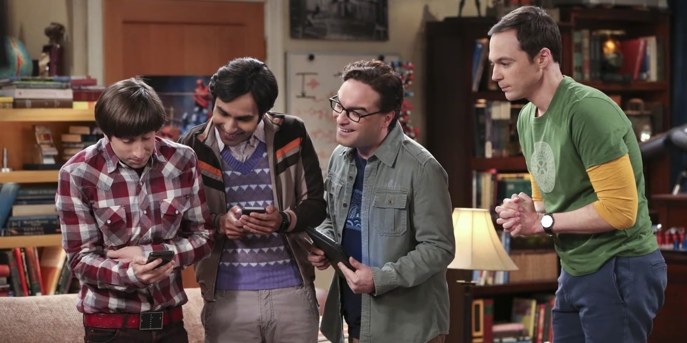 Howard, Raj, Leonard e Sheldon olham entusiasmados para seus telefones em The Big Bang Theory