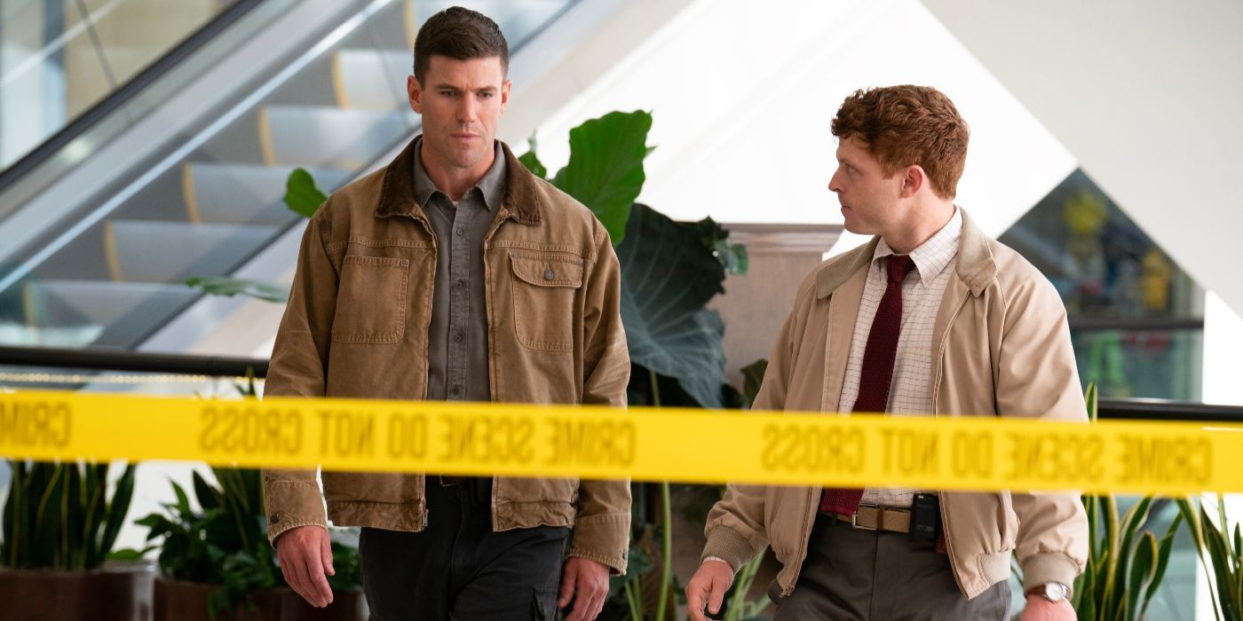 Randy olha para Gibbs (Austin Stowell) na frente de uma escada rolante de shopping em uma cena de crime em NCIS: Origins