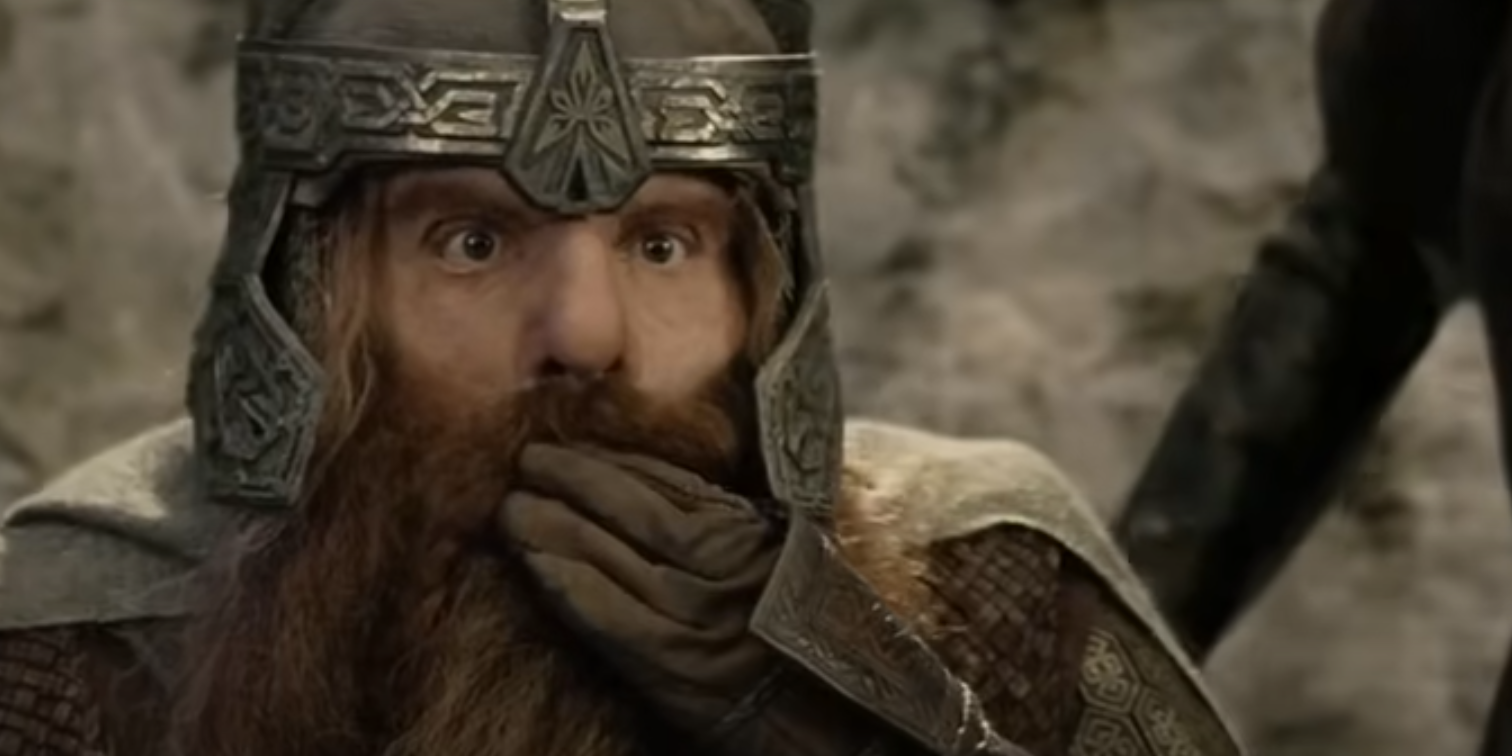 Gimli tropeça no arco de Legolas e finge alarme com a mão na boca em O Retorno do Rei.