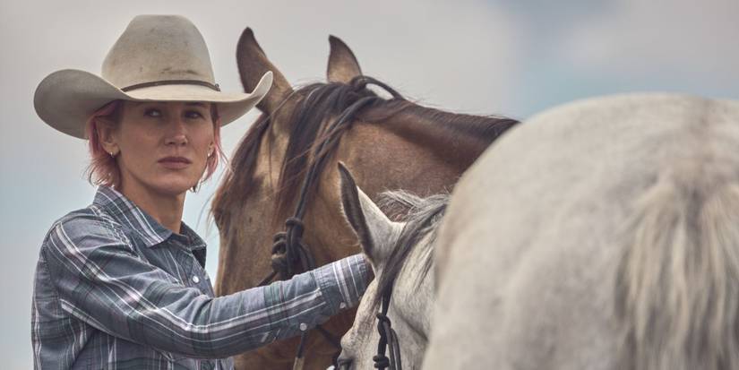 Teeter, played by Jennifer Landon, wears cowboy gear standing next to a white horse in Yellowstone.