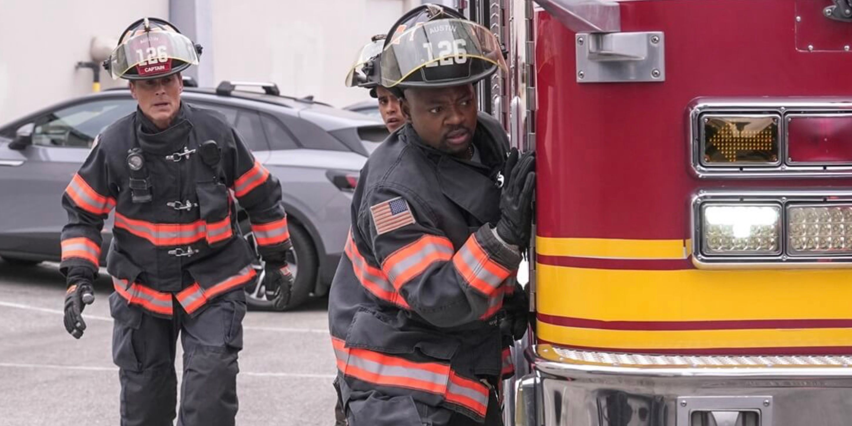 Owen and Paul wearing firefighter gear while hiding behind a fire truck on 9-1-1 Lone Star