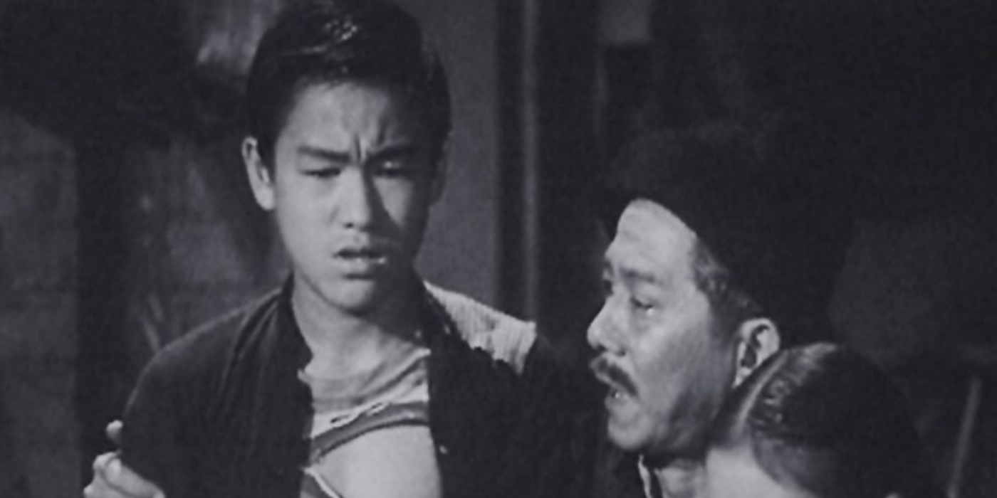 O jovem Frank Wong Fuk-wan (Bruce Lee) parece perturbado enquanto um homem o conforta em An Orphan's Tragedy.