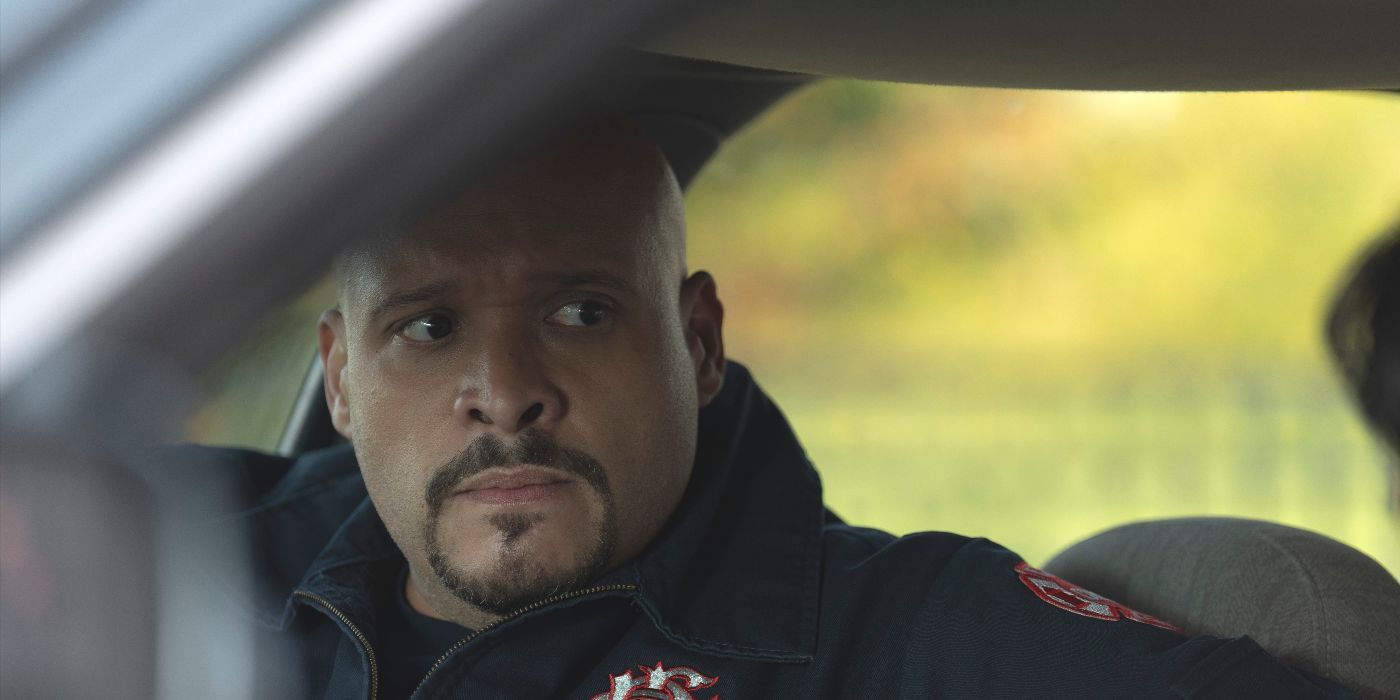 Joe Cruz (actor Joe Minoso) sits anxiously in a car wearing his Squad jacket on NBC's Chicago Fire