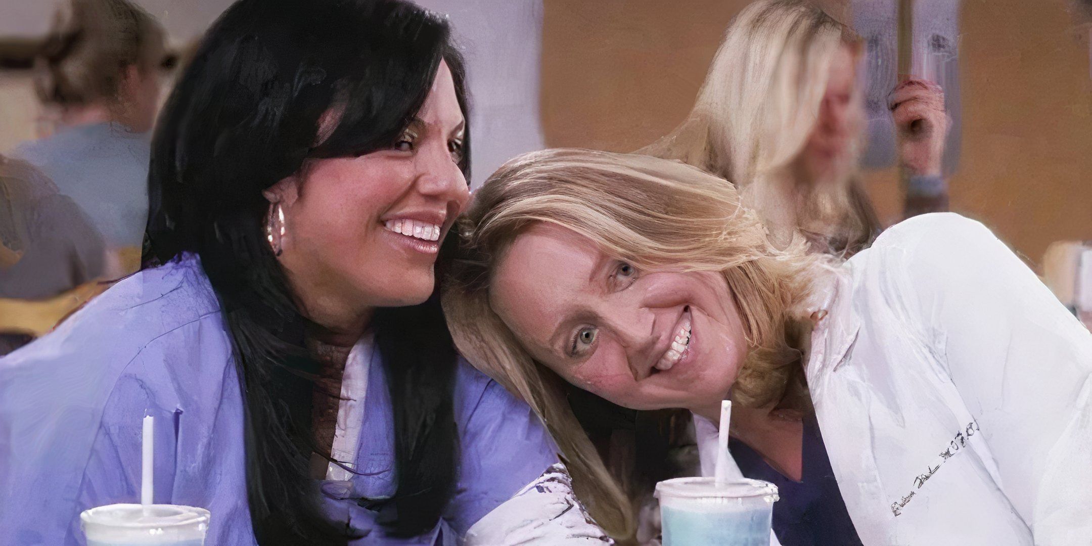 Erica Hahn deitada no ombro de Callie Torres enquanto os dois riem no refeitório em Grey's Anatomy.