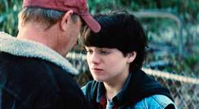 Kevin Costner as Jonathan Pa Kent back to camera comforting young Clark in a junkyard from the Man of Steel Movie
