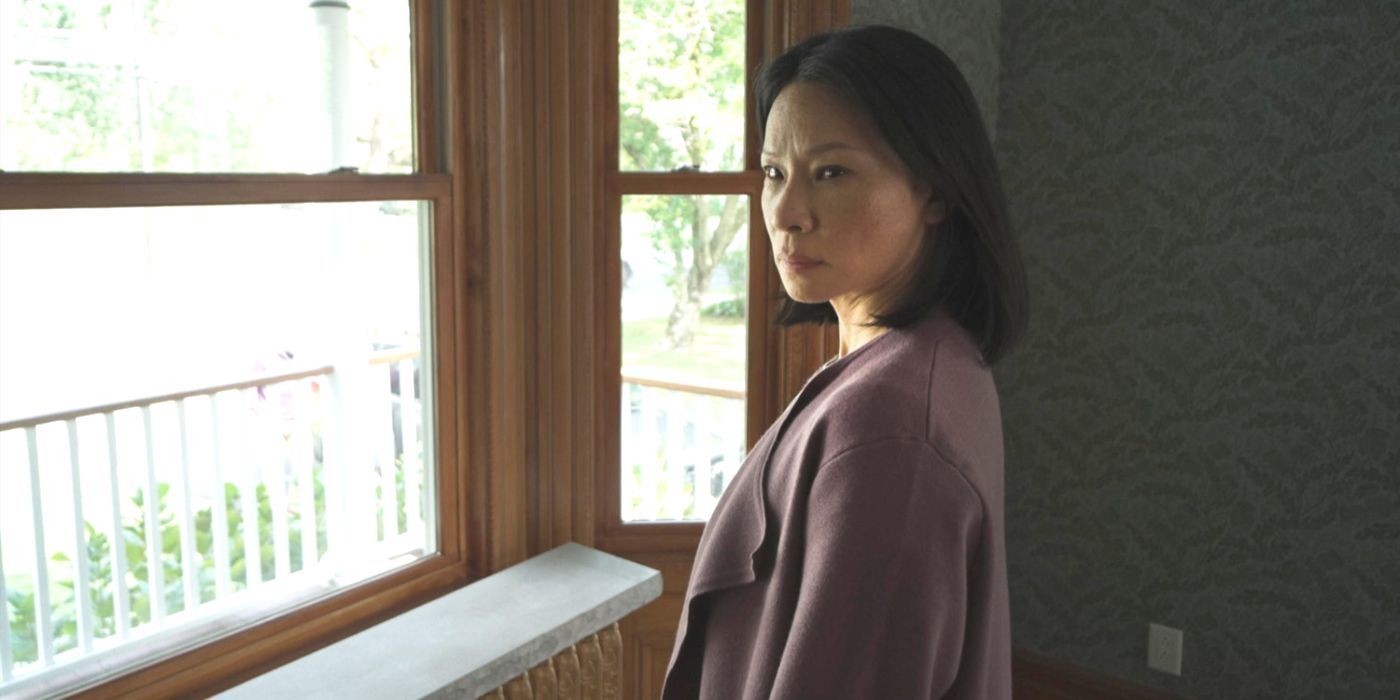 Rebecca, interpretada por Lucy Liu, fica em frente a uma janela em um suéter rosa na presença do filme