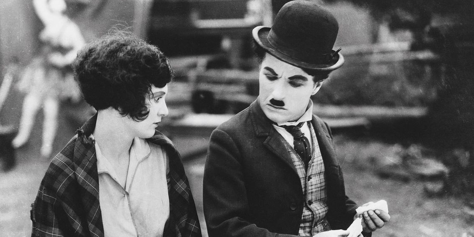 Charlie Chaplin está sentado do lado de fora com uma mulher no Circo.