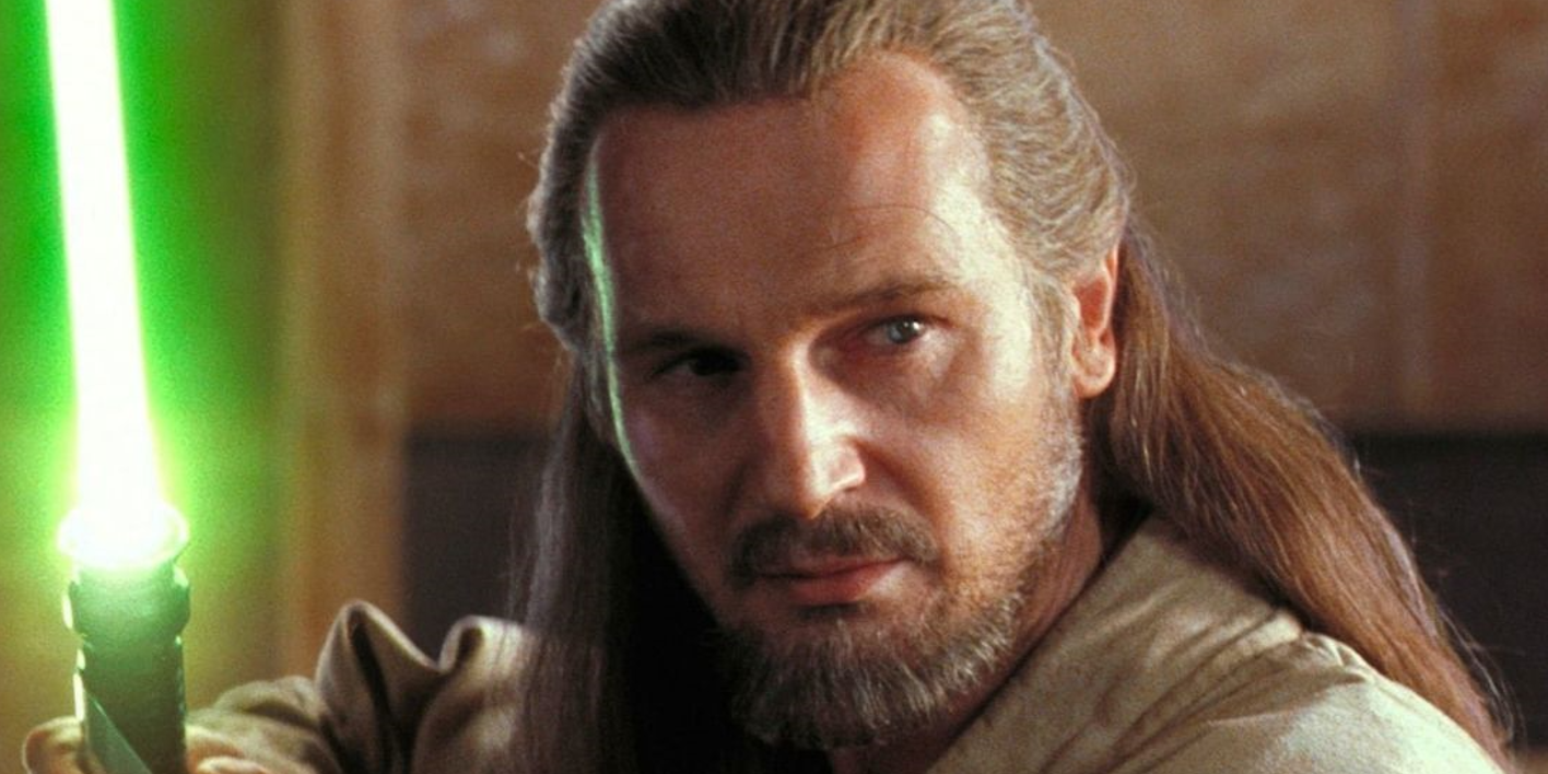 Liam Neeson segura seu sabre de luz em Star Wars.