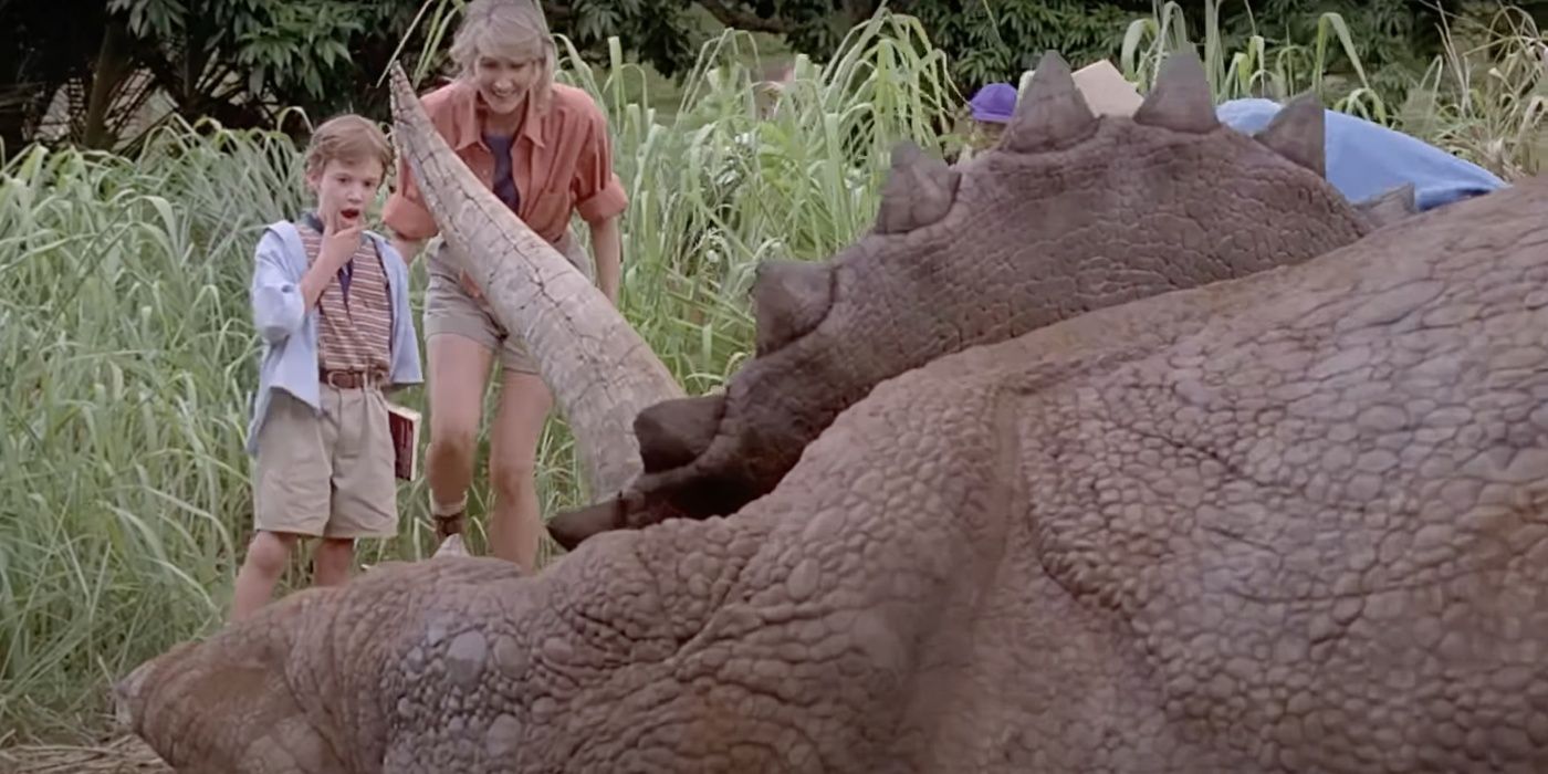 Joseph Mazzello como Tim Murphy e Laura Dern como Ellie Sattler olha para Triceratops em Jurassic Park