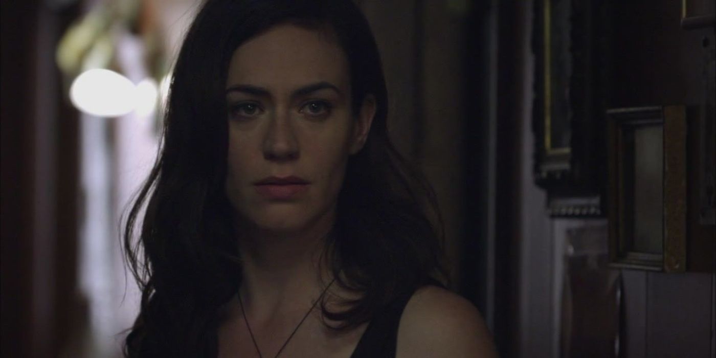 Tara Knowles (Maggie Siff) fica em frente a uma parede de fotos de família em filhos da anarquia.