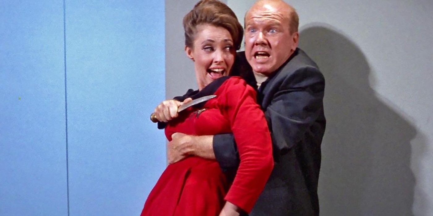 Um homem segurando uma mulher sob a mira de uma faca em Star Trek TOS.