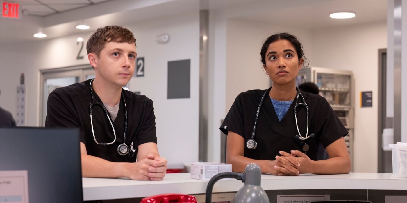 Whitaker e Samira, ambos vestindo uniforme azul, encostados no balcão de um hospital, olhando para cima no The Pitt