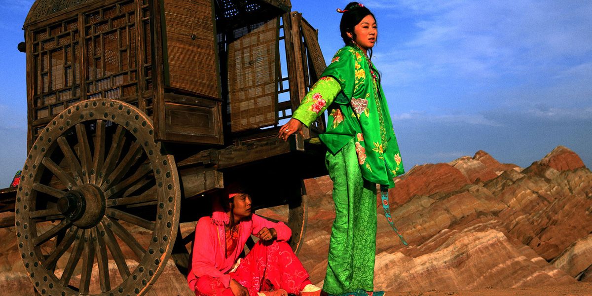 Li (Xiao Shenyang) senta -se sob um carrinho enquanto seu amante (Yan Ni) olha por cima da borda de um penhasco em uma história simples de macarrão.