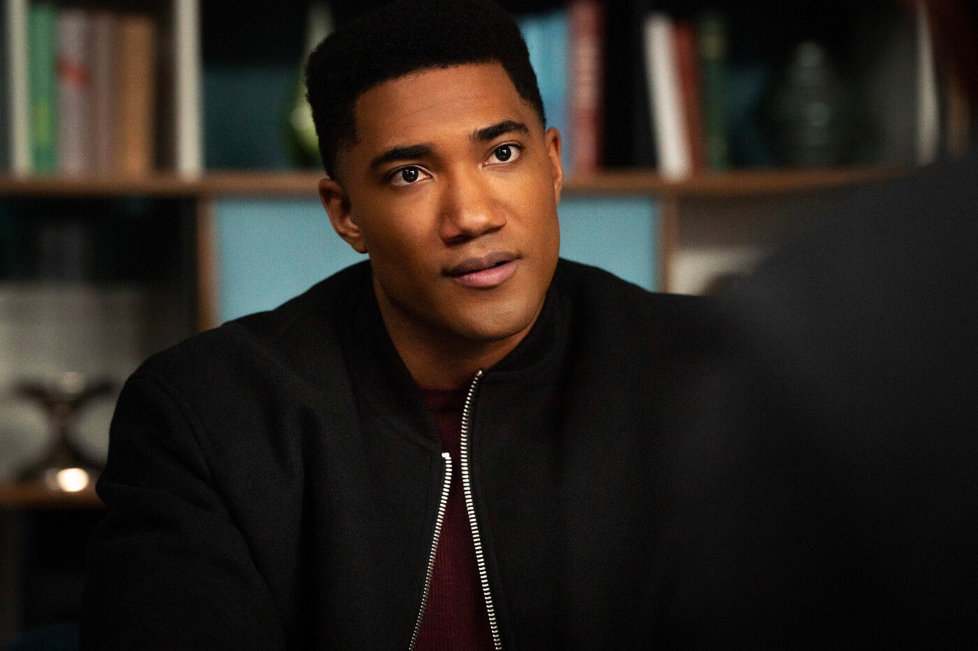 Andre Raines, played by actor Carter Redwood, wearing a black bomber jacket in FBI: International