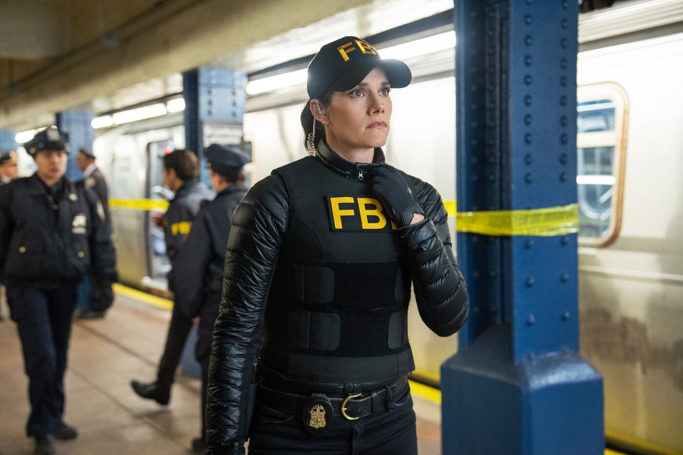 Maggie Bell (Missy Peregrym), wearing a black FBI vest and cap, stands on a subway platform in FBI