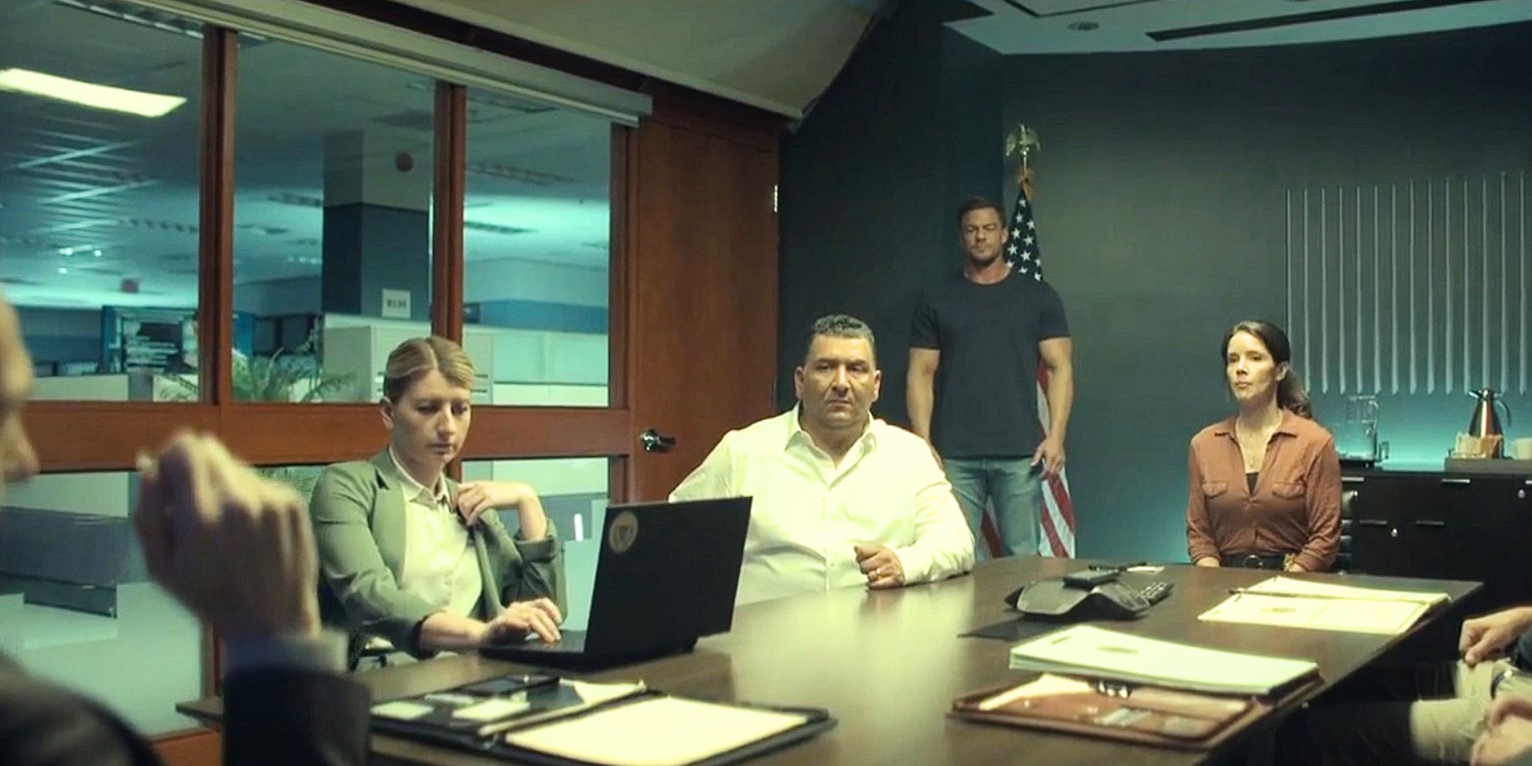 Susan Duffy Guillermo Villanueva and a group of men in suits sit around a table with Reacher standing in the back