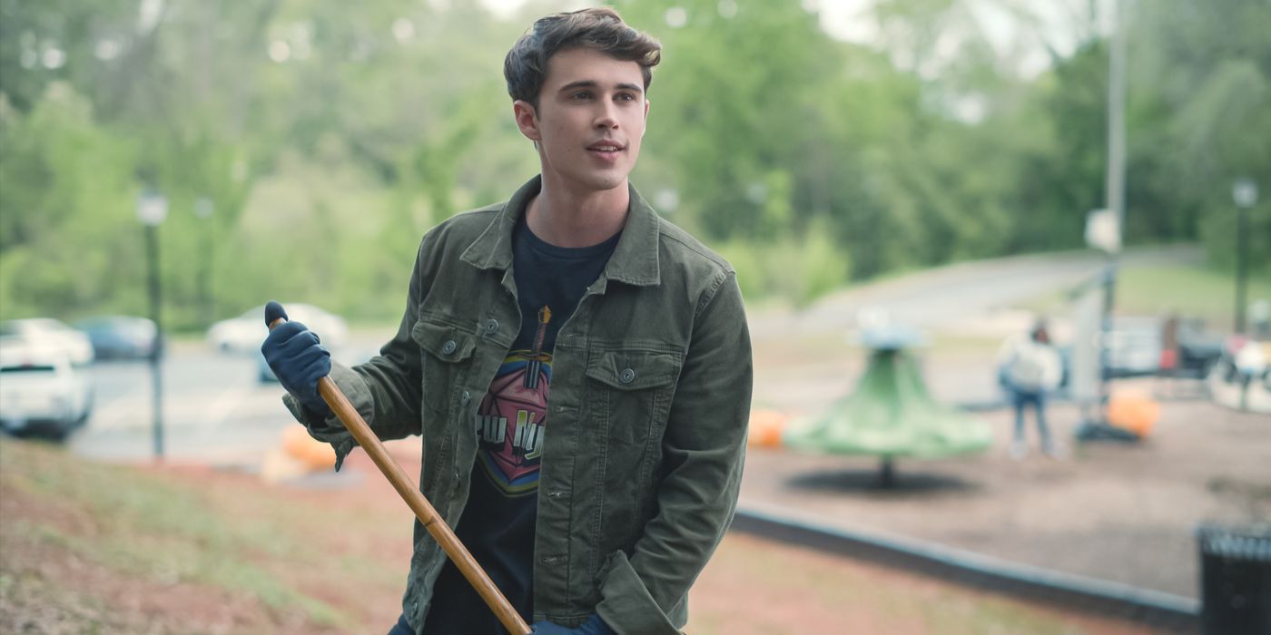 Kyle (Logan Allen) holding a rake, wearing black denim jacket in Netflix's Sweet Magnolias Season 4