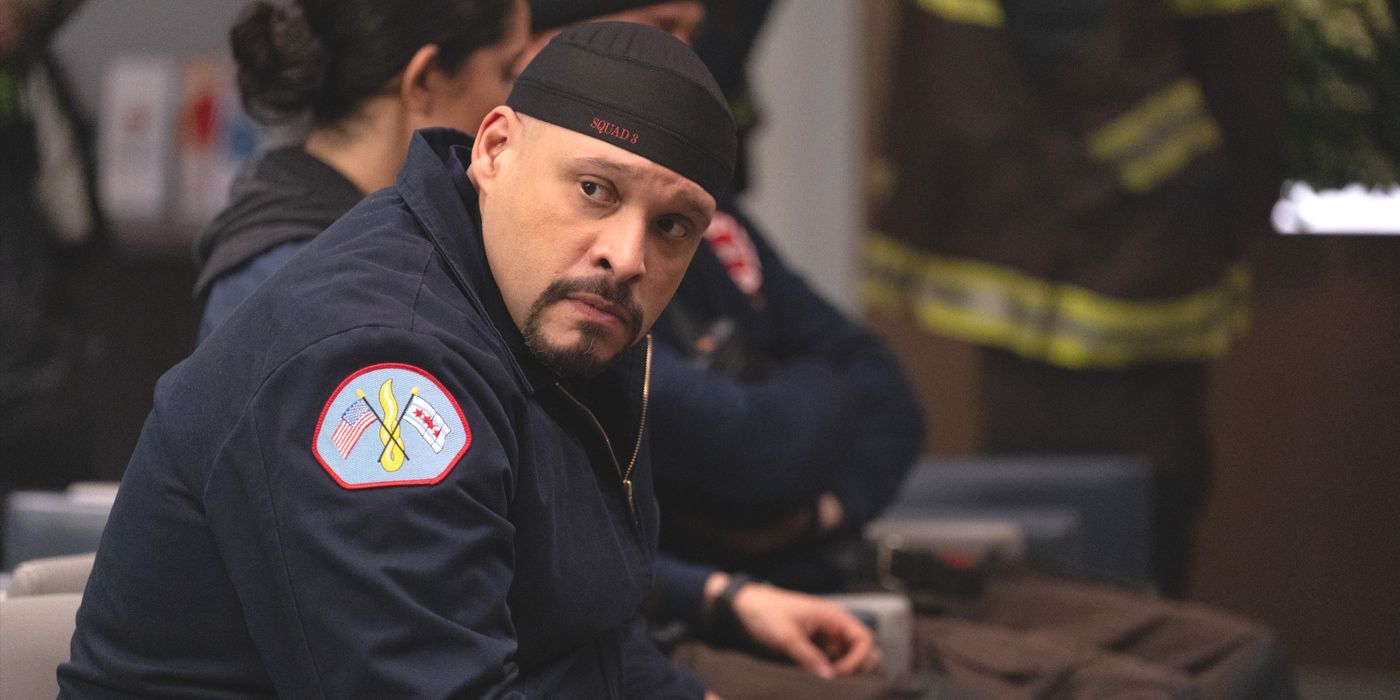 Joe Cruz (actor Joe Minoso) sits in his blue firefighter jacket and backwards hat in Chicago Fire