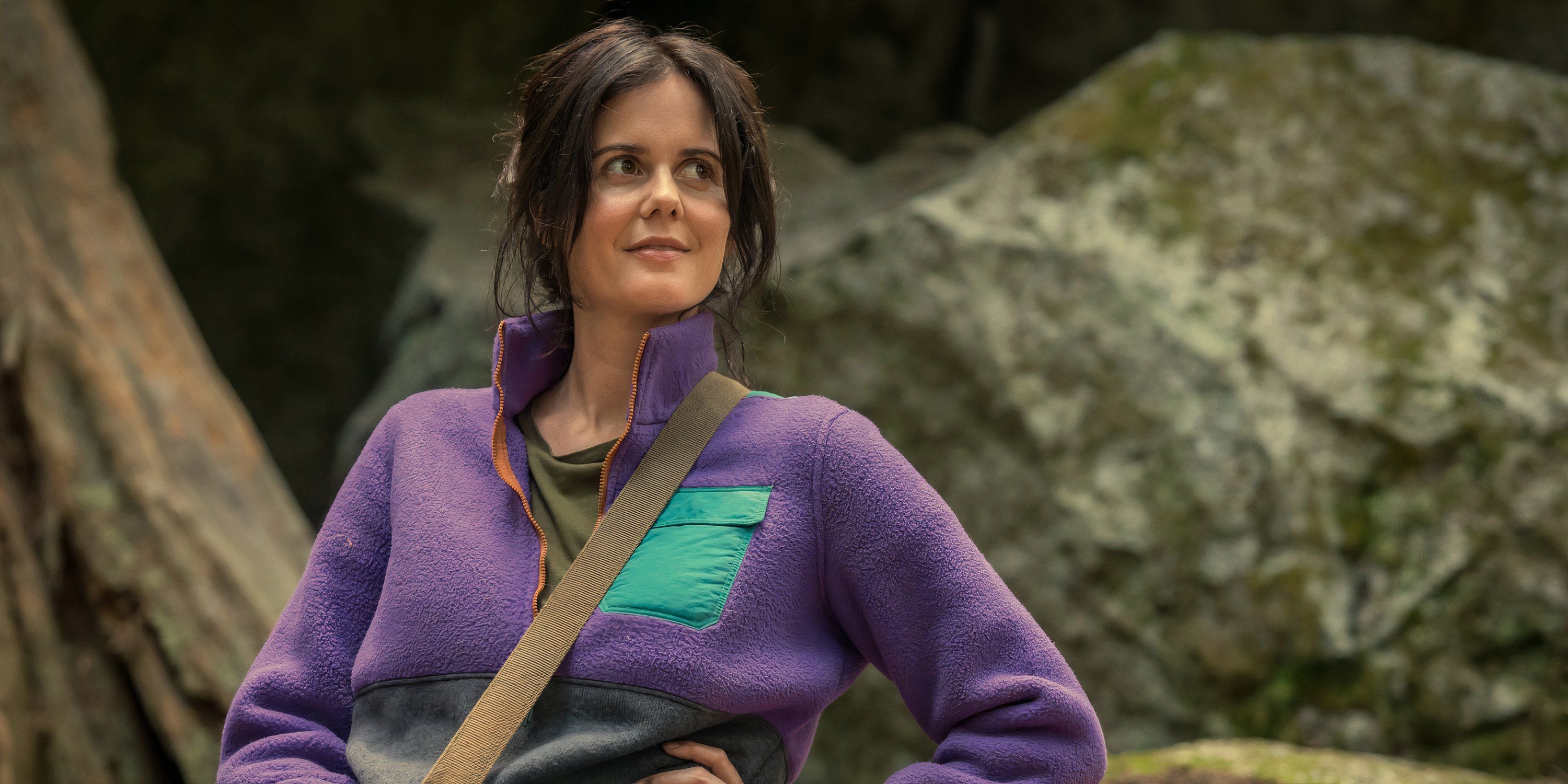 Hannah smiles in front of a boulder in Yellowjackets