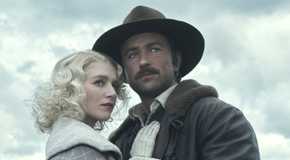 Spencer Dutton, wearing a brown suit, holding Alexandra Dutton in a grey coat from the TV show 1923