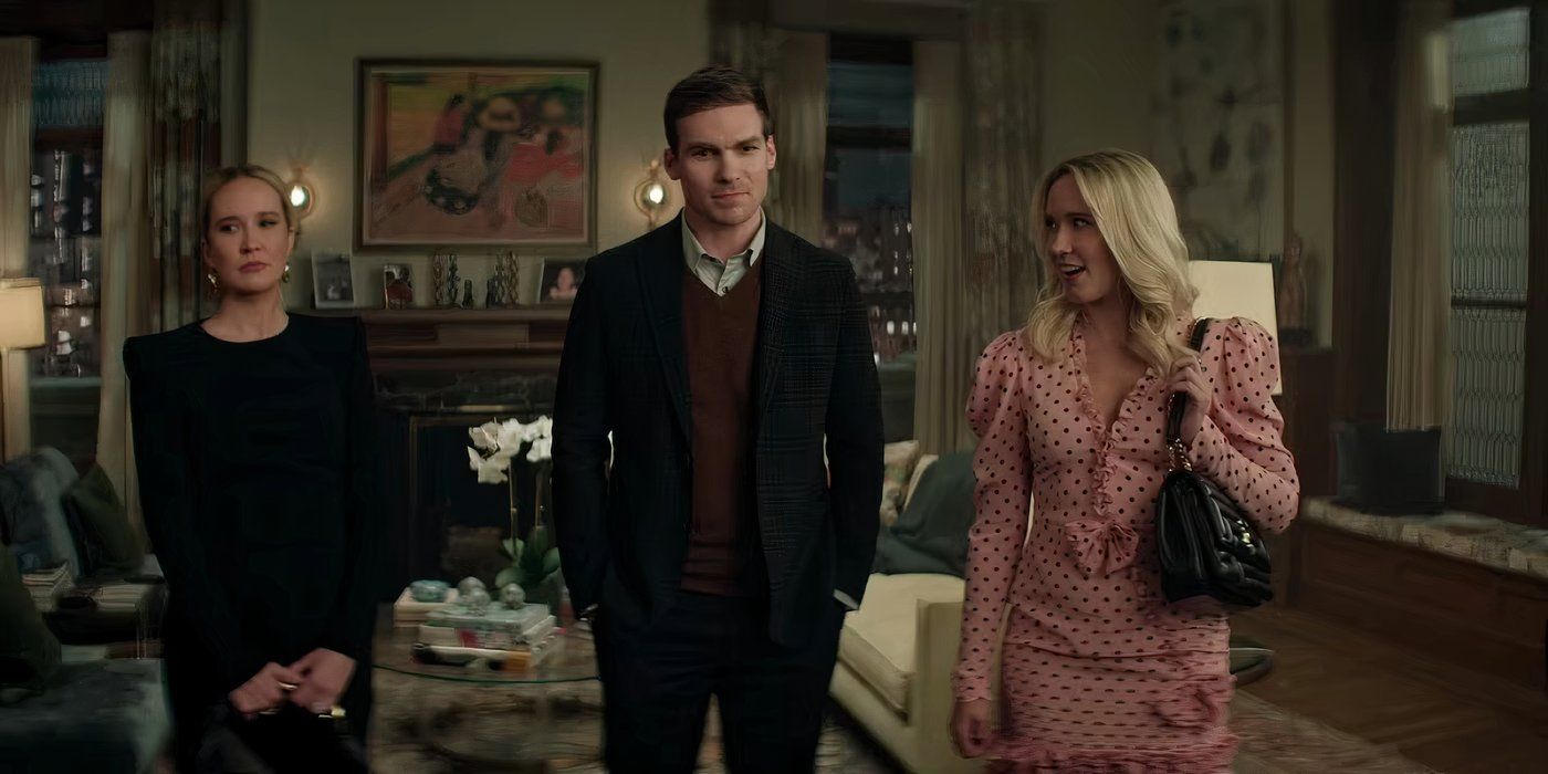 Joe Goldberg, vistiendo un traje de tres piezas, está entre dos mujeres en una sala de estar en You Temporada 5