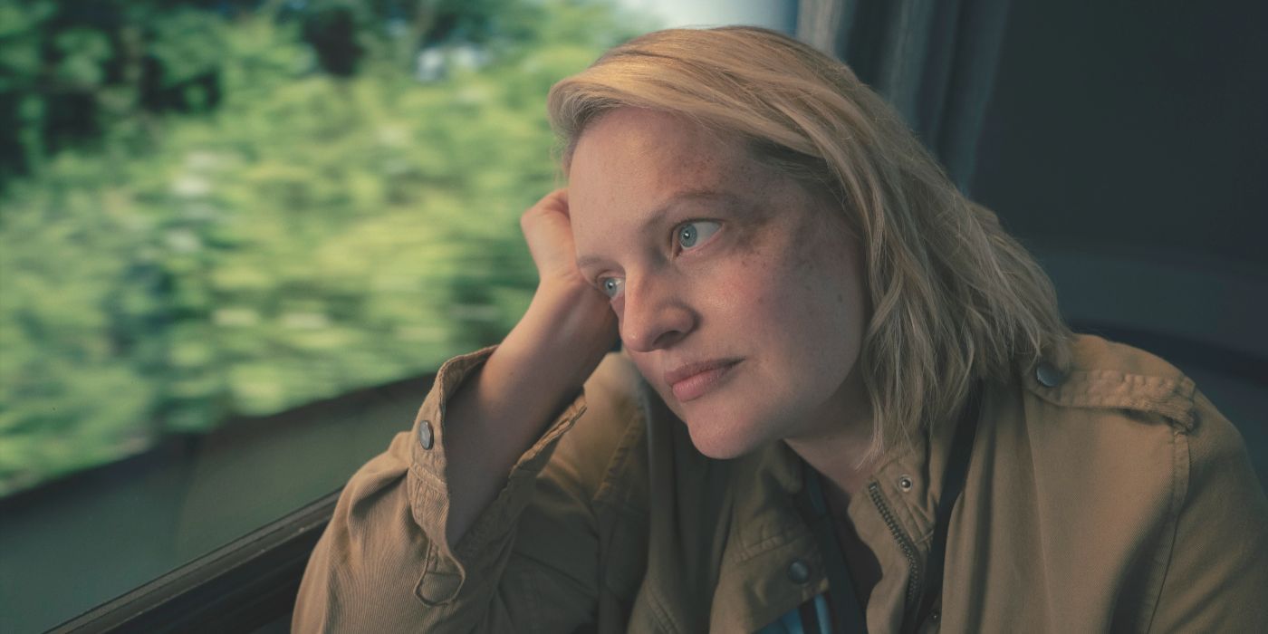 June, wearing a brown coat, leans her head in her hand against a train window in The Handmaid's Tale