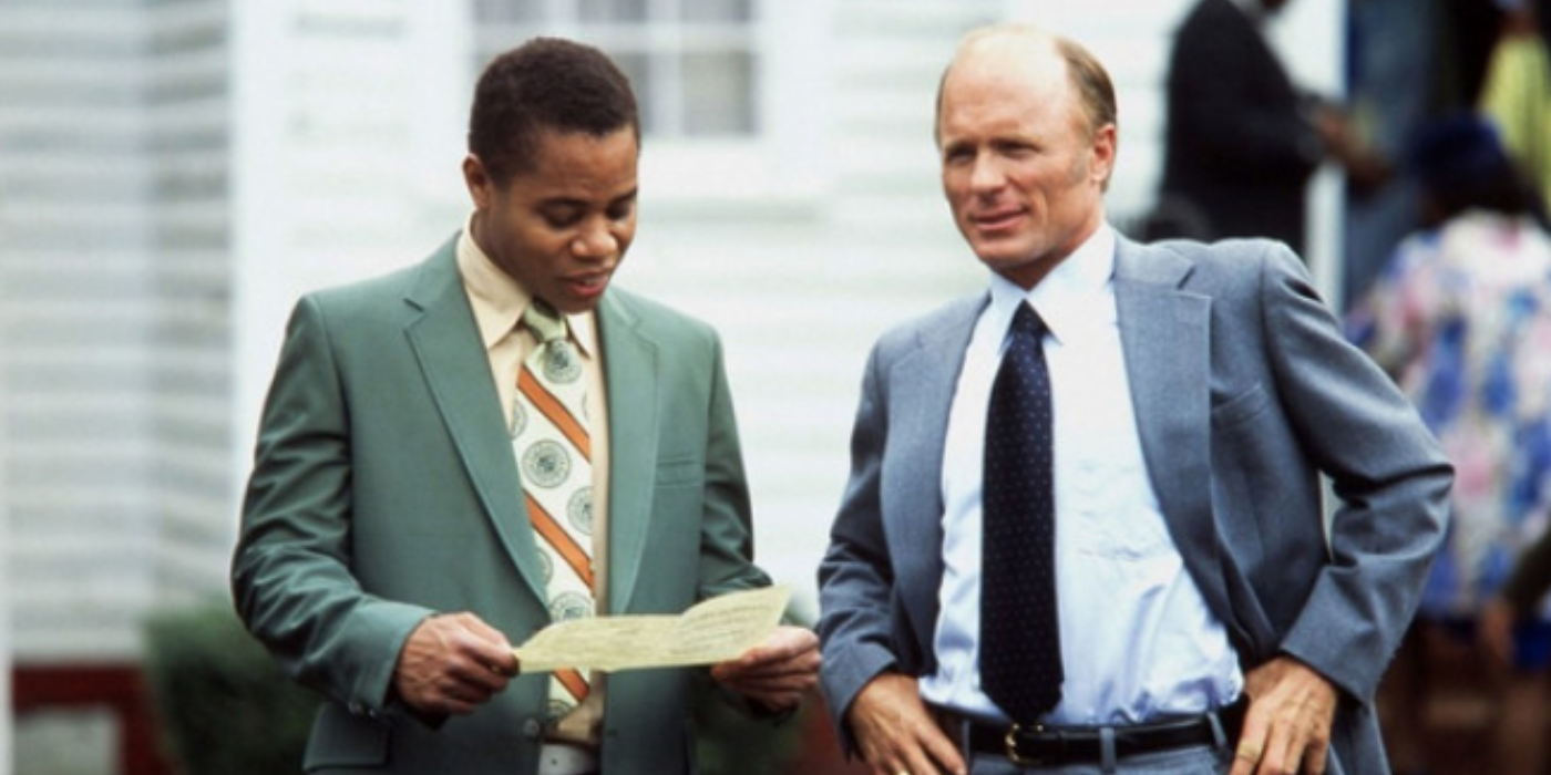 Radio (Cuba Gooding Jr.) is smiling while standing next to Coach Jones (Ed Harris) in Radio (2003).