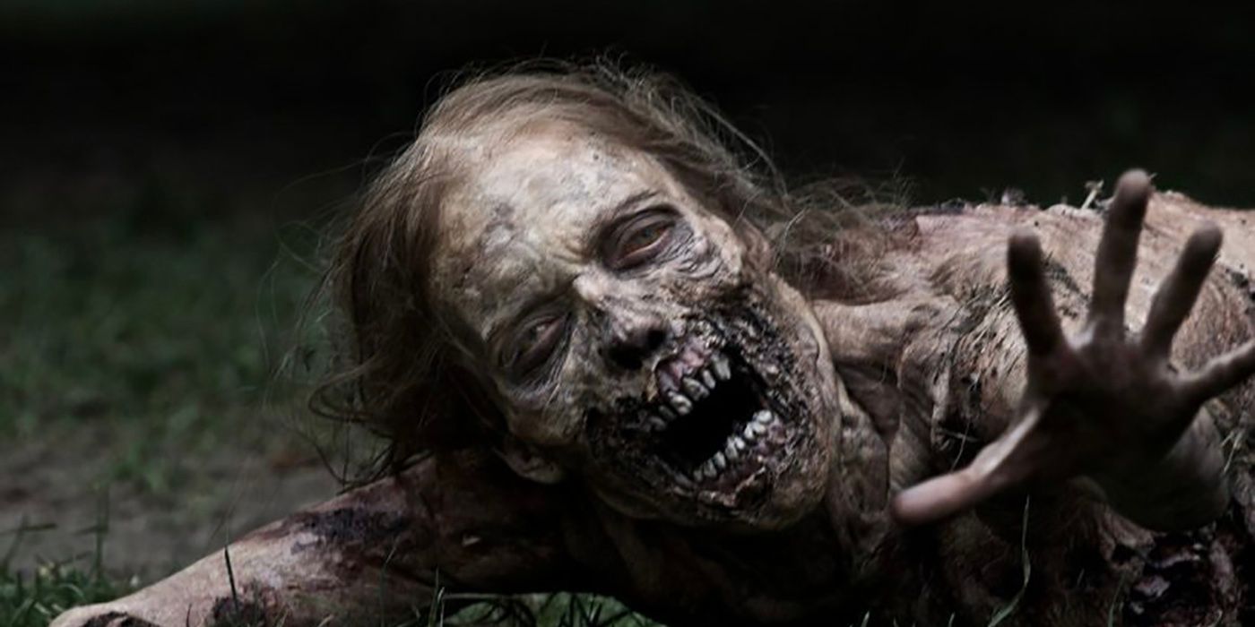 A young reanimated woman on the ground reaching her hand out, reduced to a skeleton in The Walking Dead.