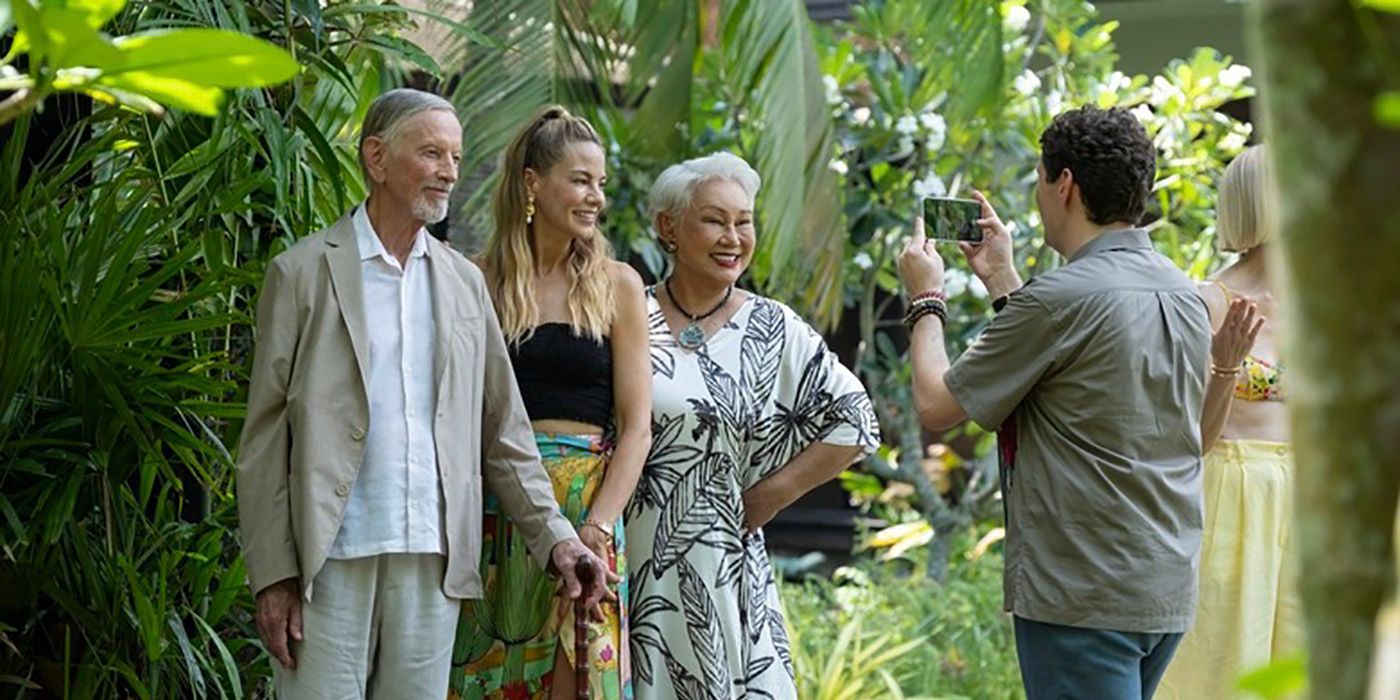 A photographer taking a photo of Jim and Sritala with Jacklyn in the white lotus.