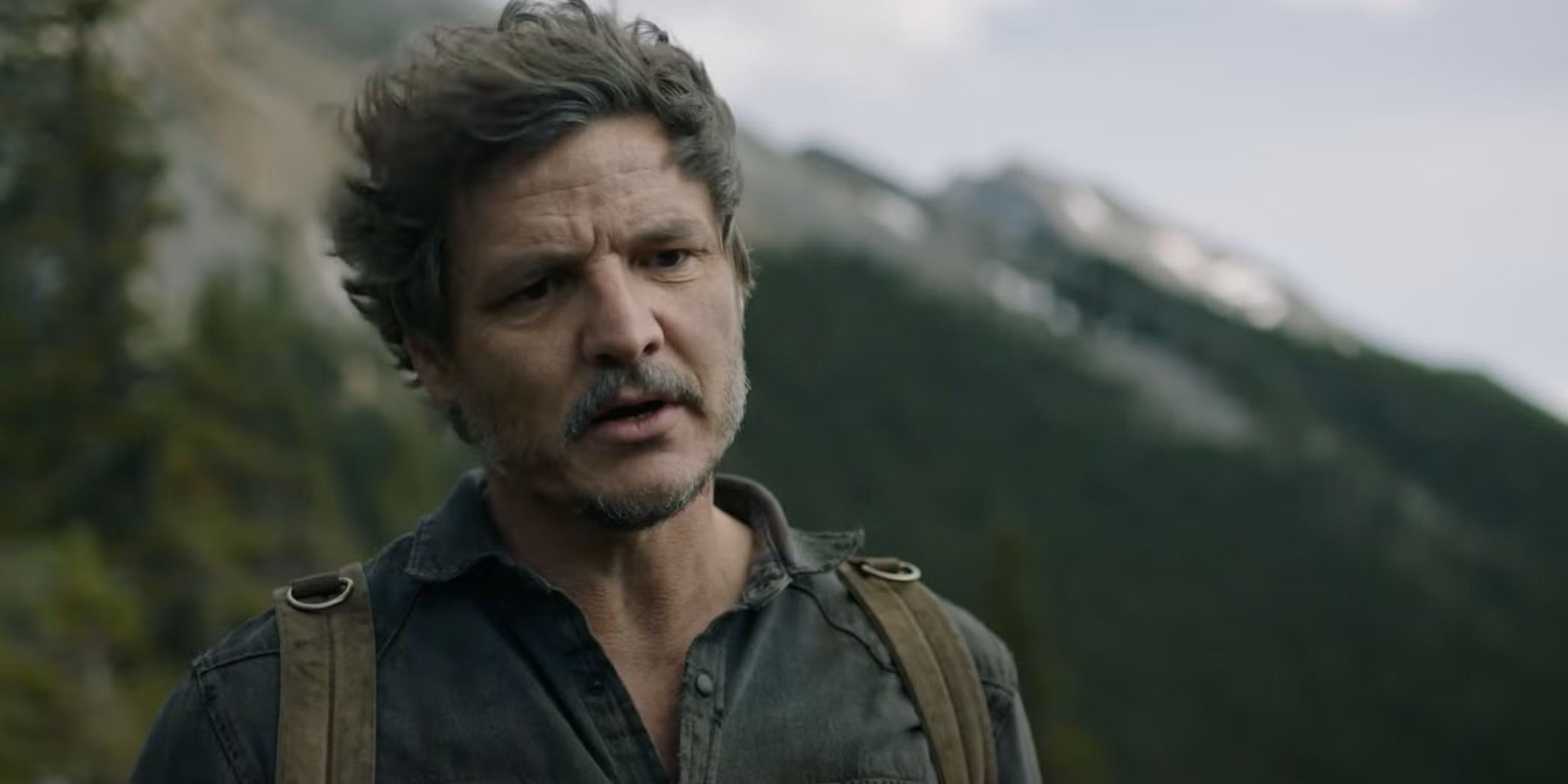 The Last of Us' Joel speaks in front of a mountain.