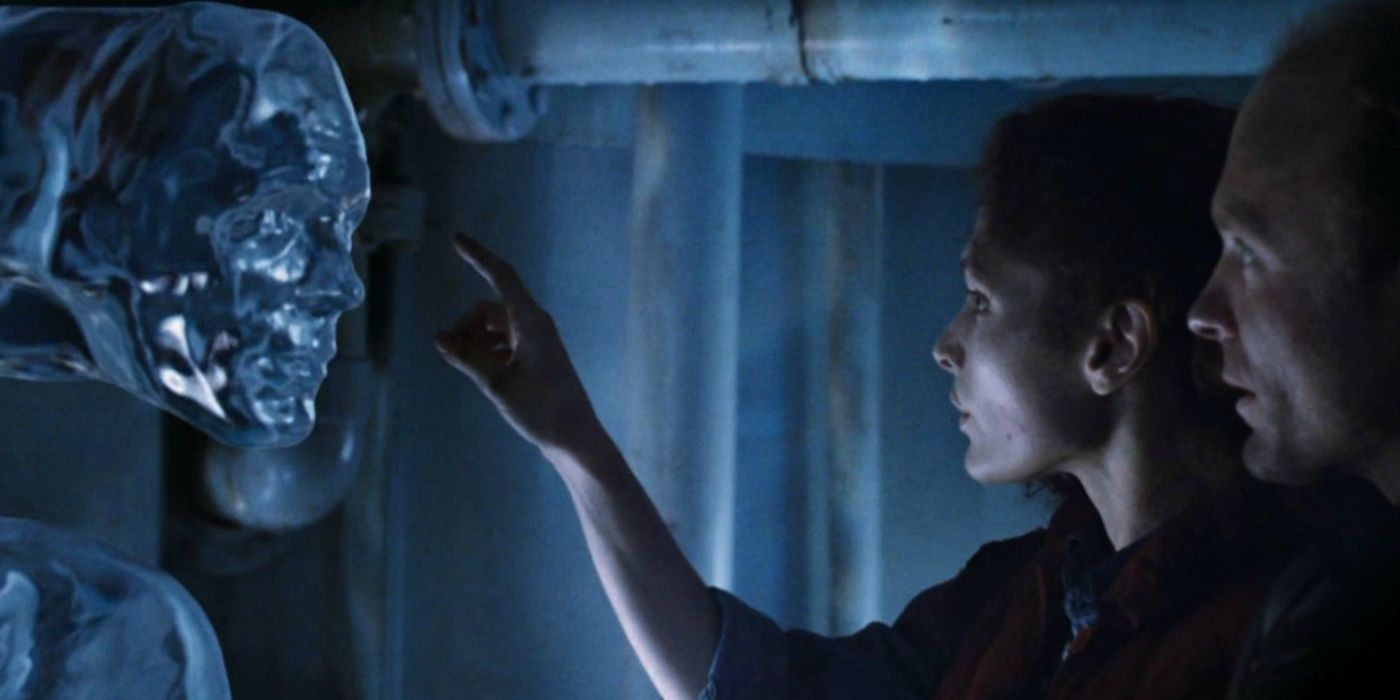 Dois personagens de The Abyss examinam um rosto de aparência humana formado na água