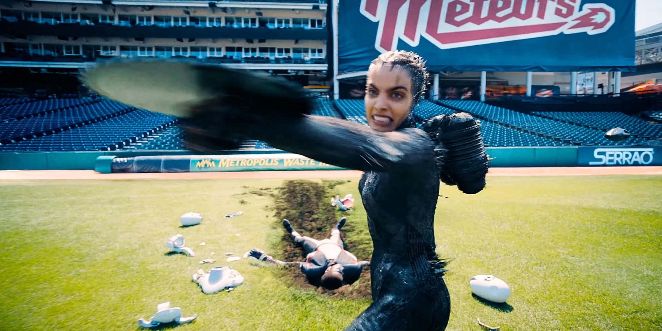 The engineer grimacing and launching a saw in a baseball stadium, Monsieur formidable unconscious behind her of Superman 2025