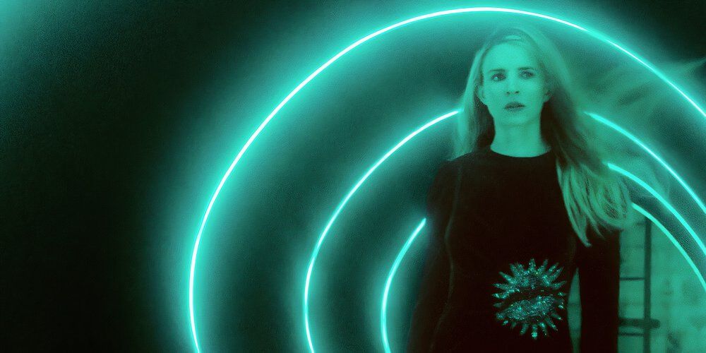 A woman walking through a tunnel of neon lights