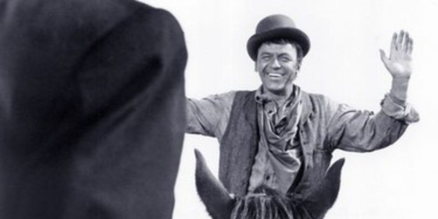 Frank Sinatra as dingus magee smiling on horseback with arms in surrender in Diry Dingus Magee