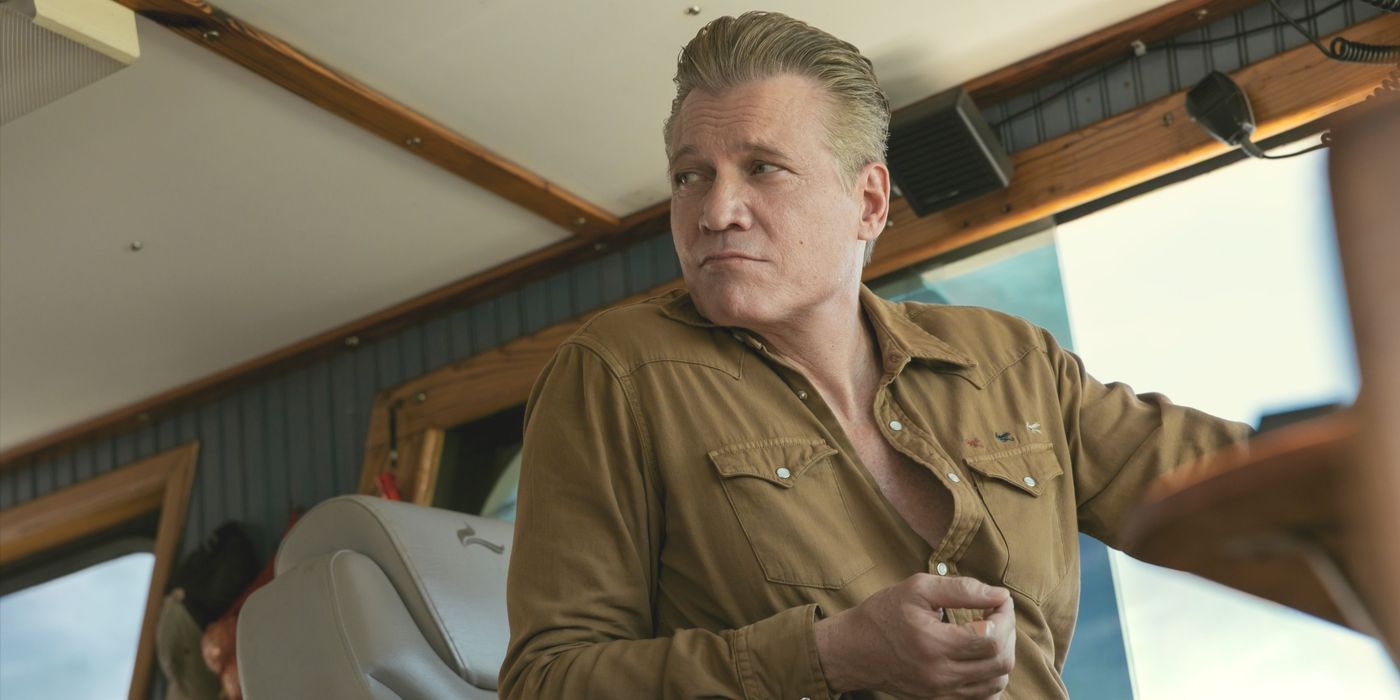 Harlan, played by Holt McCallany, wearing a brown shirt and at the wheel of a boat in The Waterfront