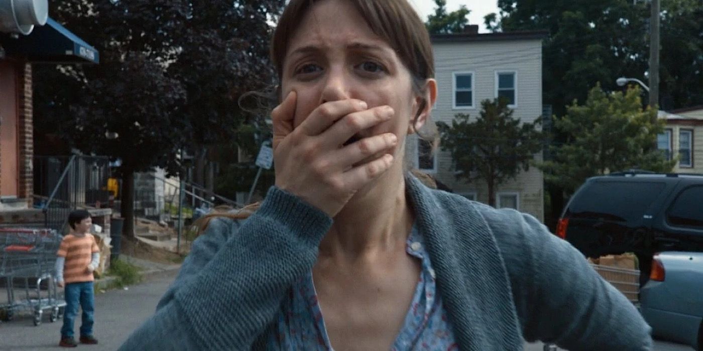 A woman covers her screams with her hand.