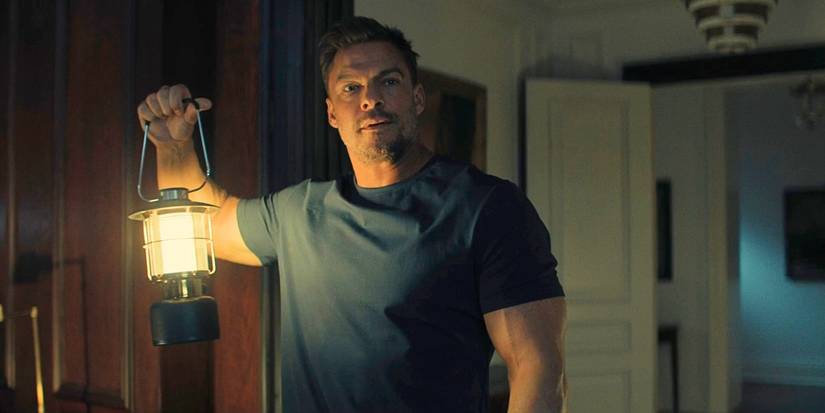 Alan Ritchson as Reacher holding a lantern in Reacher