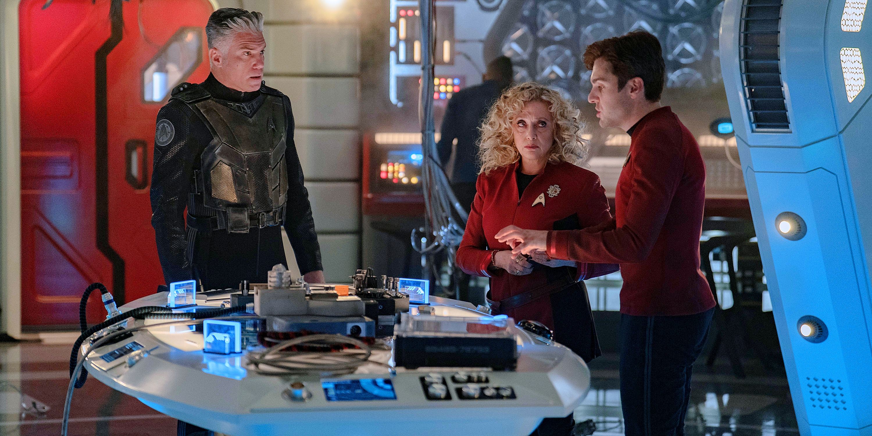 Captain Pike in battle armor next to Pelia and Scotty in the Engineering lab from Star Trek Strange New Worlds