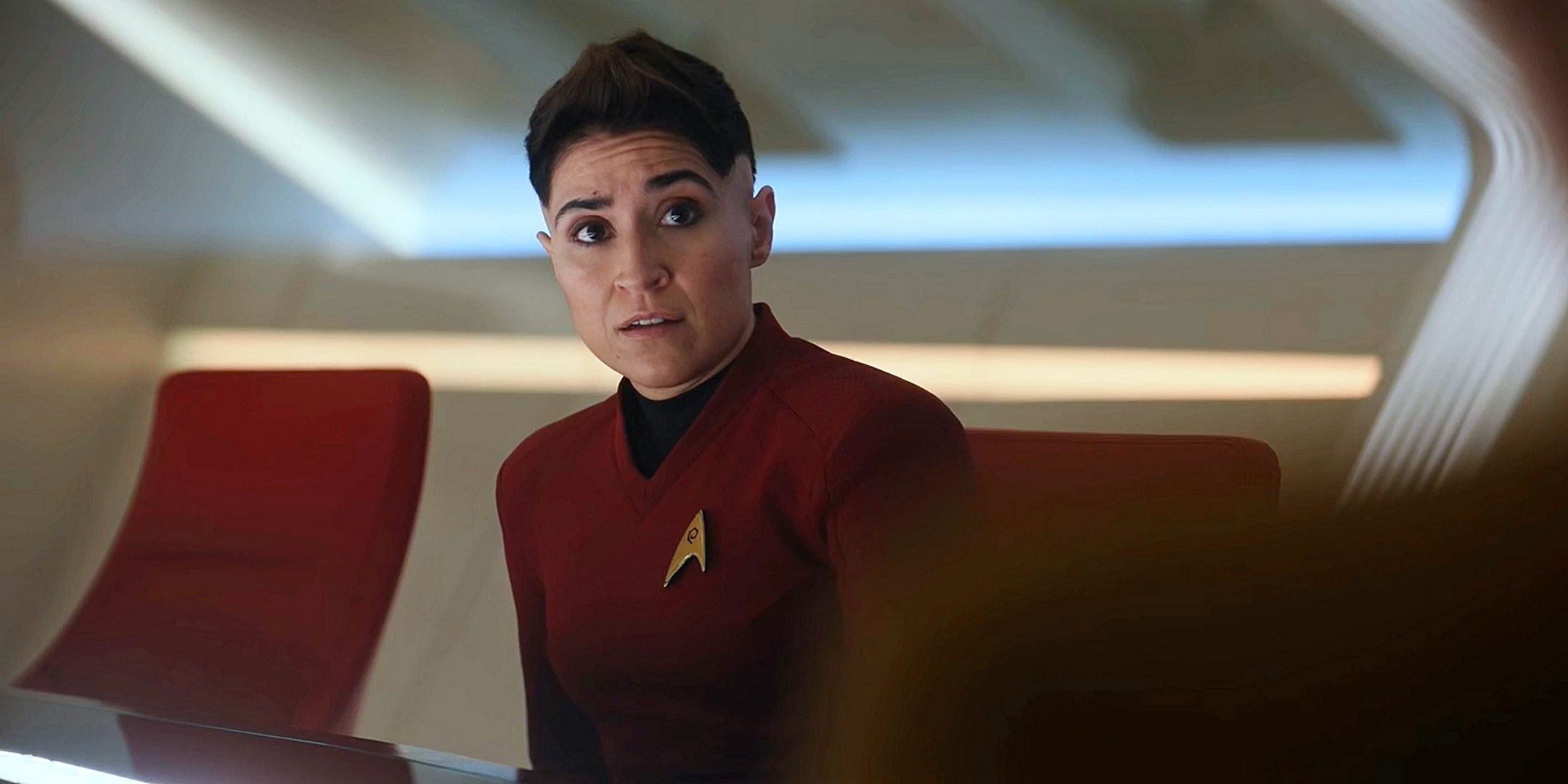 Erica Ortegas in her red uniform looking concerned while seated at the table in the Enterprise ready room