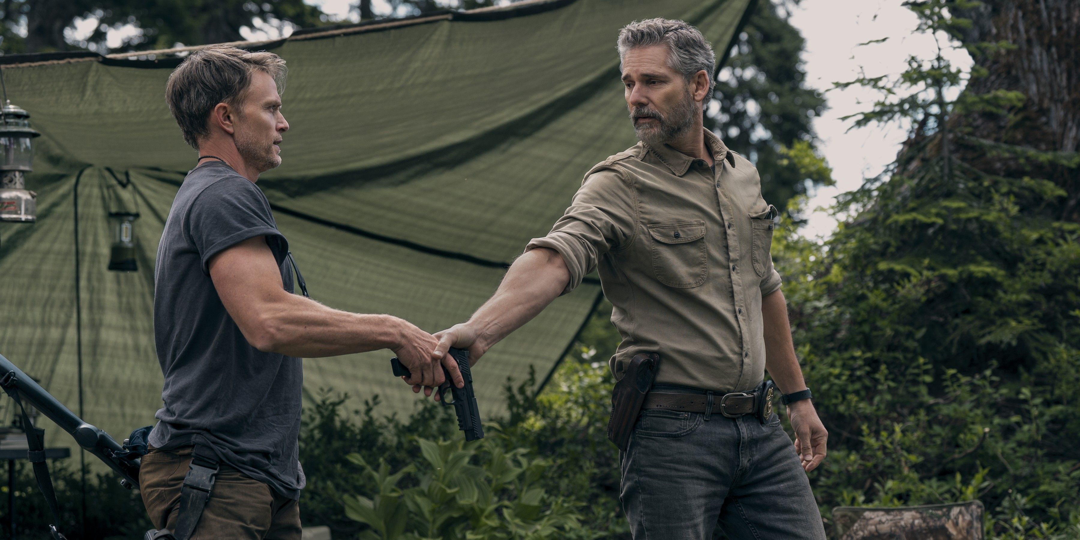 Kyle Turner (Eric Bana) entrega uma pistola a Shane Maguire (Wilson Bethel) em um acampamento em Untamed