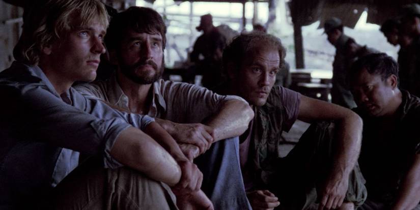 Four men sit on the ground in the killings fields.