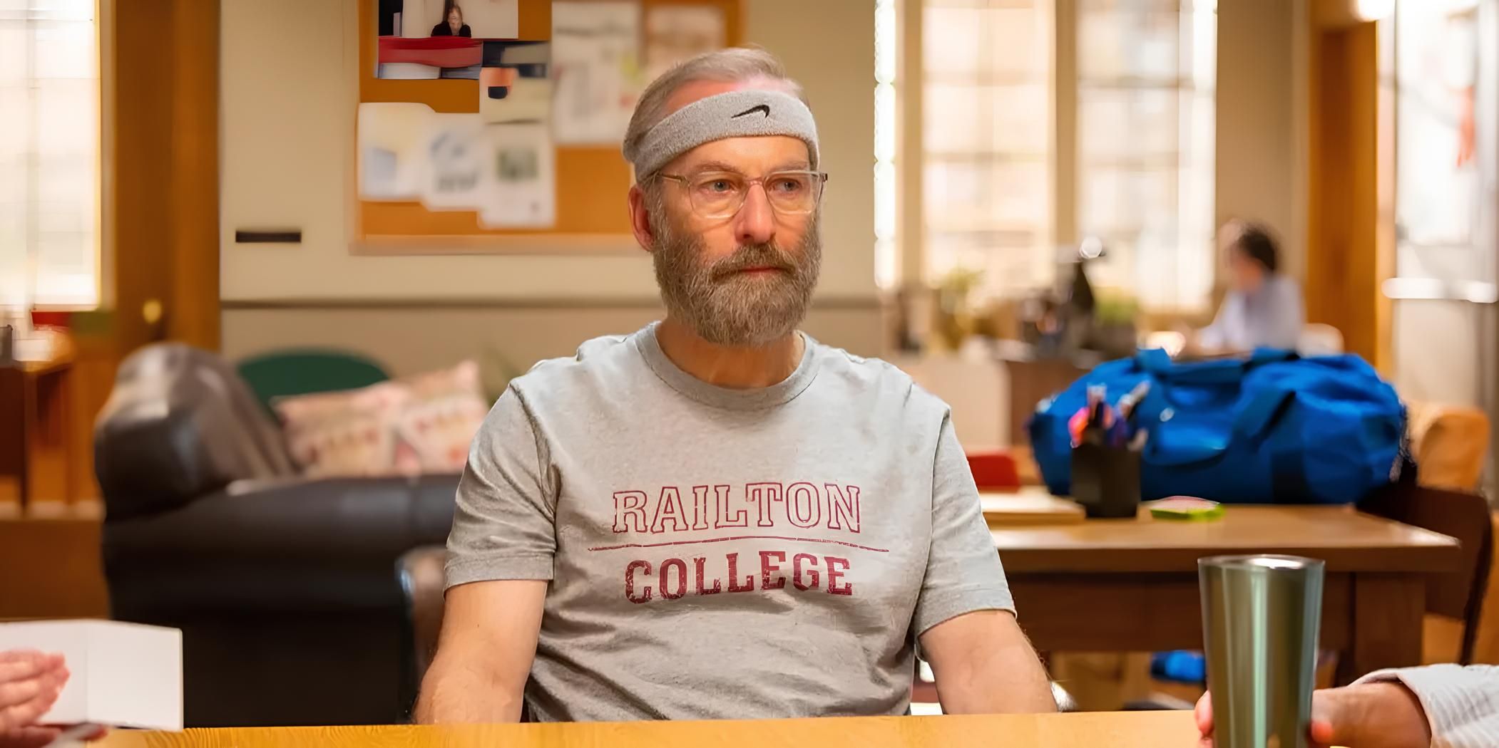 Hank Devereaux, Jr. (Bob Odenkirk) is sitting in a meeting wearing sweat clothes in Lucky Hank.