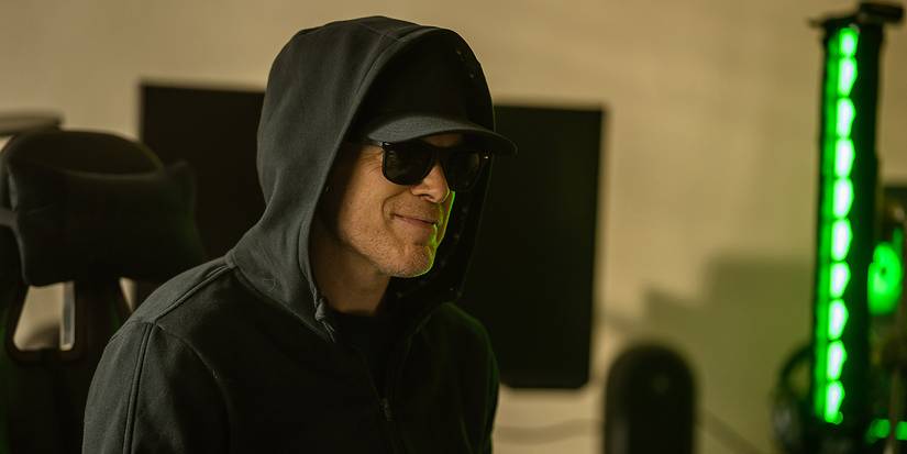 Dexter smiling while wearing sunglasses, a baseball cap and hoodie in Dexter: Resurrection.