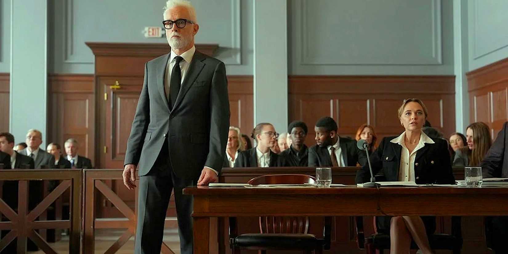 John Slattery like Leo Drummond standing in the courtroom next to a table with Madison Isemann like Sarah Plankmore of the Rainmaker series